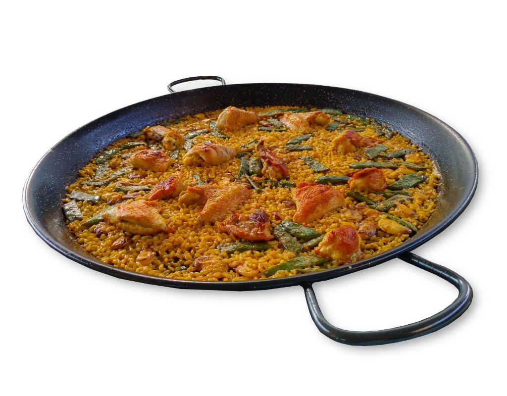Paella Valenciana in een authentieke paellapan Paella Valenciana met kip en groenten in een traditionele zwarte paellapan