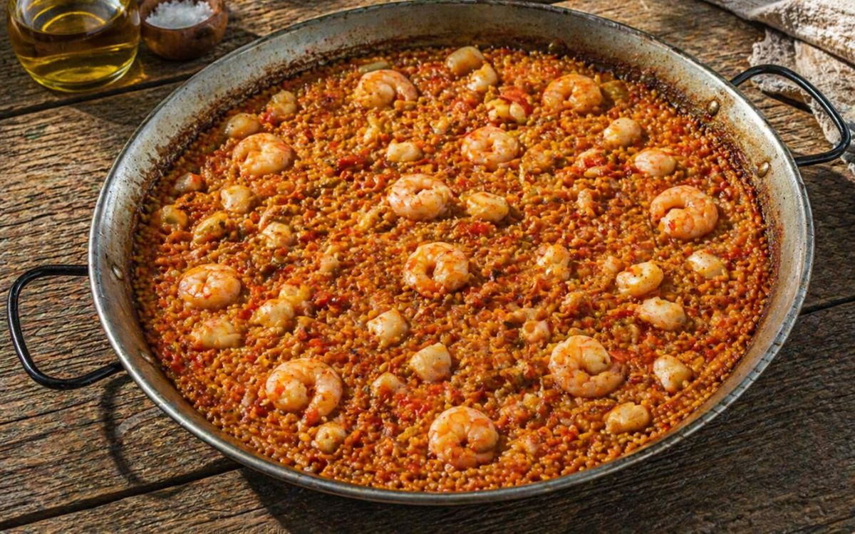 Paella del Senyoret met gepelde garnalen en stukjes inktvis in een traditionele paella pan