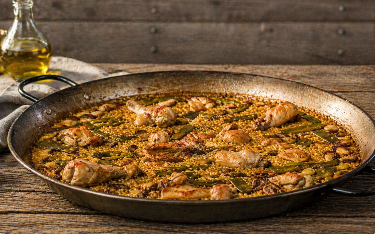 Paella Valenciana met kip, sperziebonen en bonen in paella pan.