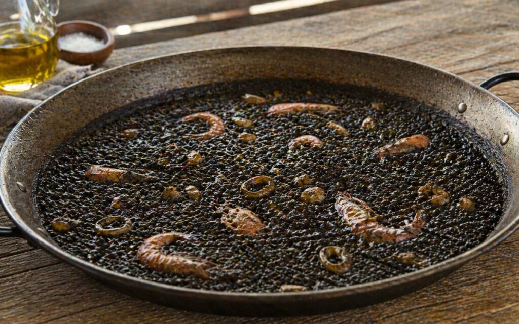 Zwarte paella met garnalen en inktvis (arroz negro) in paella pan